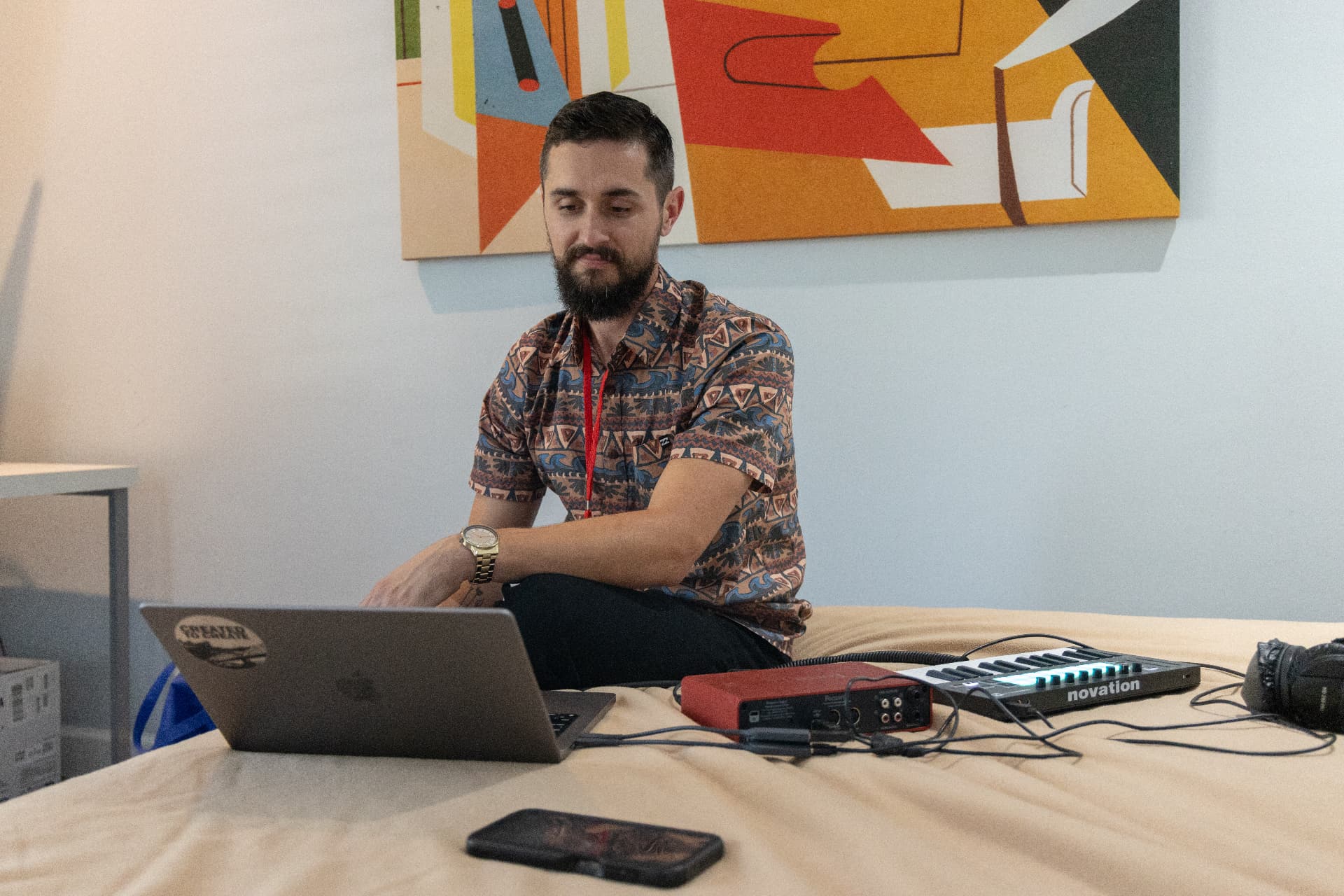 Producer with a laptop and keyboard controller on a bed