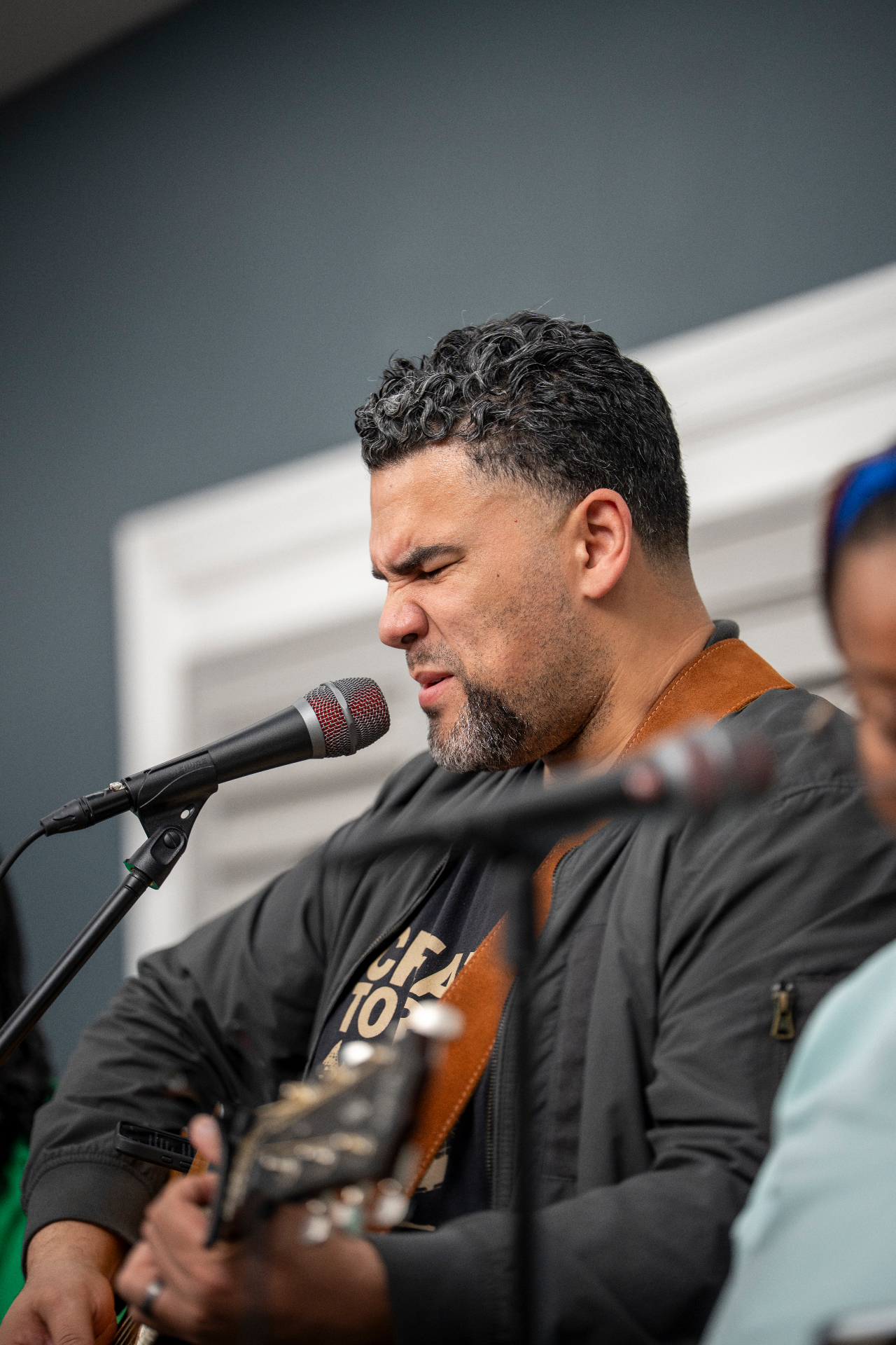 Close-up of a guitarist singing into a microphone during a performance