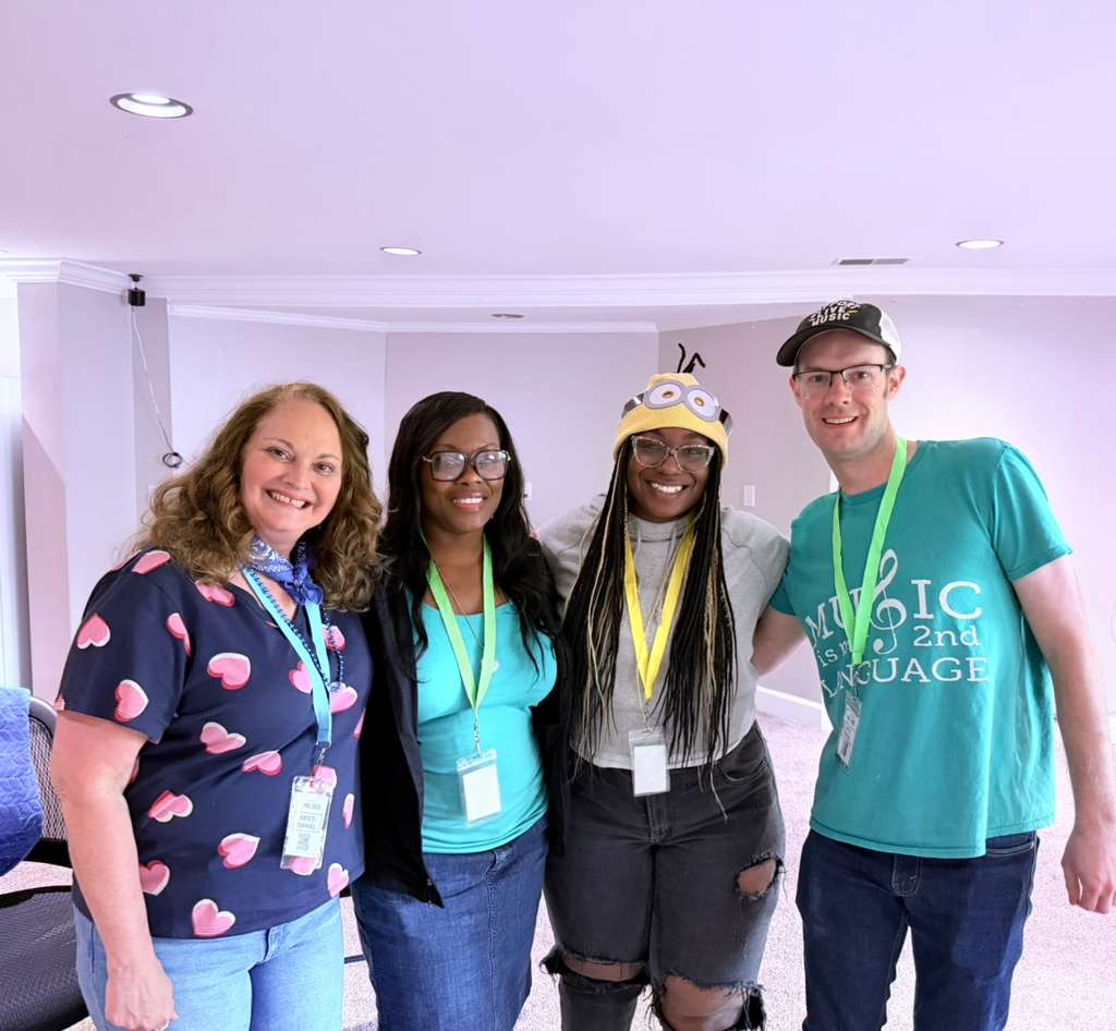 Four attendees smiling together with lanyards