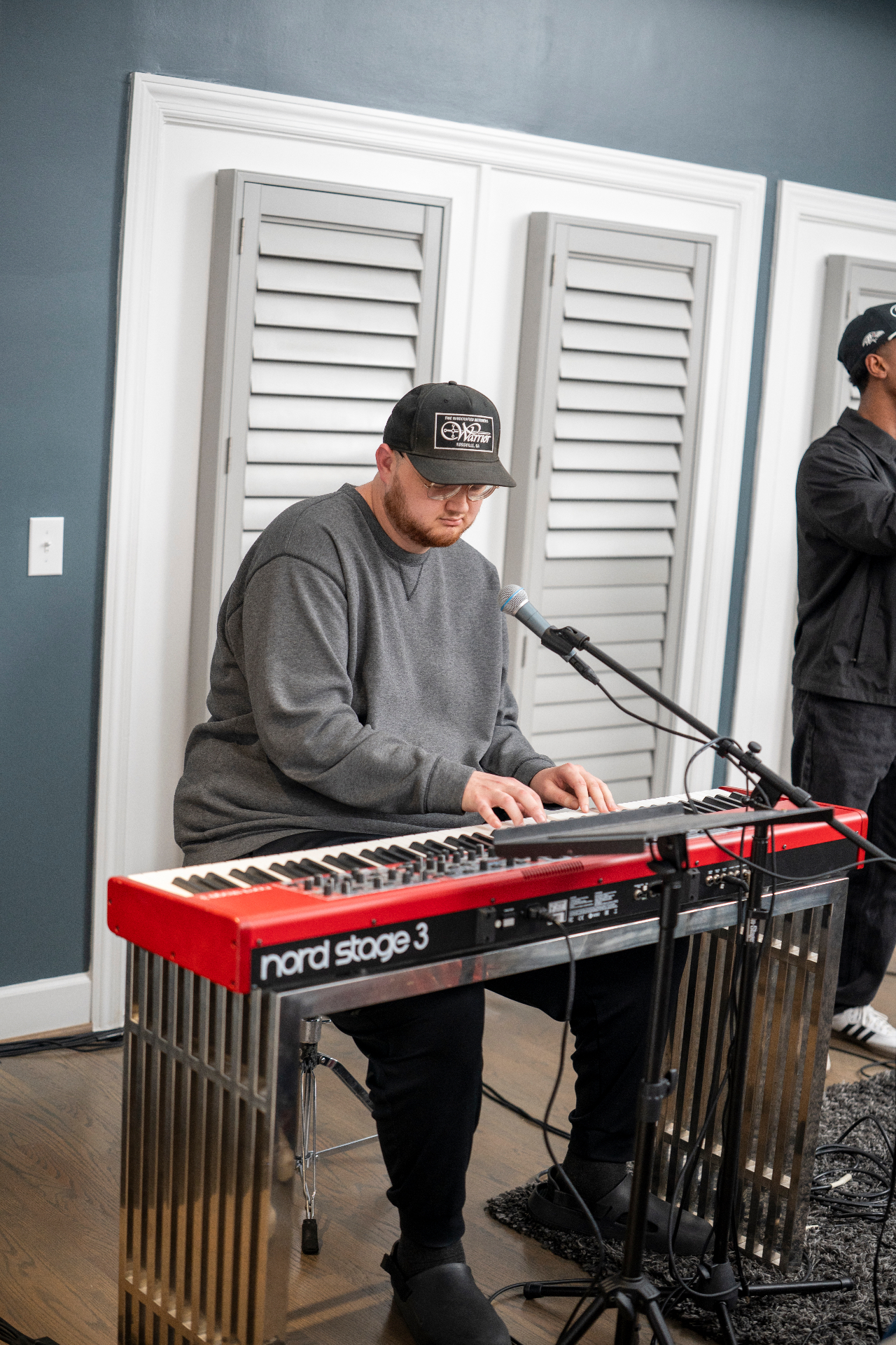 Keyboard player performing live with a microphone and red piano