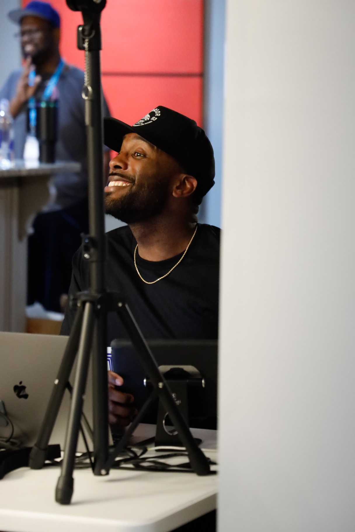 Attendee in a black cap smiling up at the stage during a session