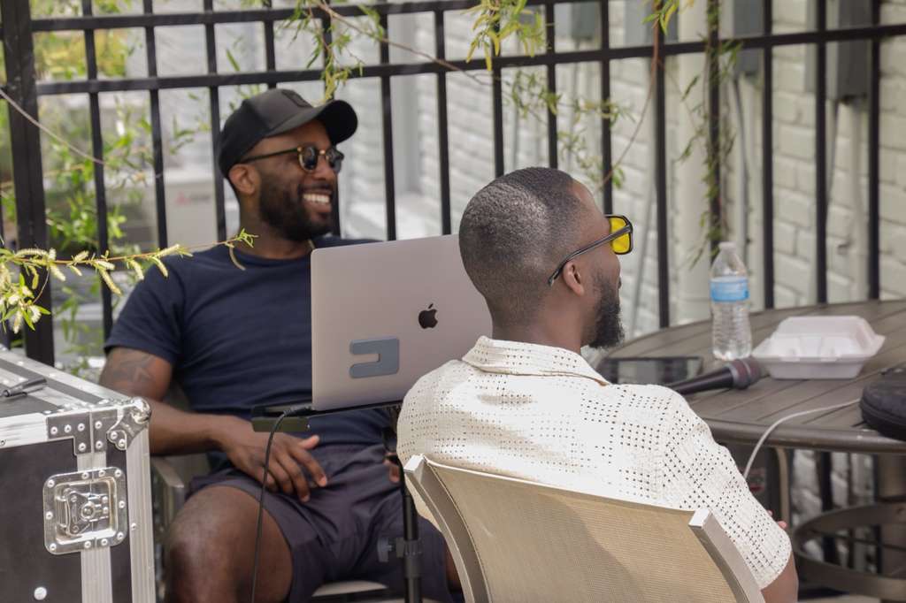 Two writers laughing together over a laptop outside