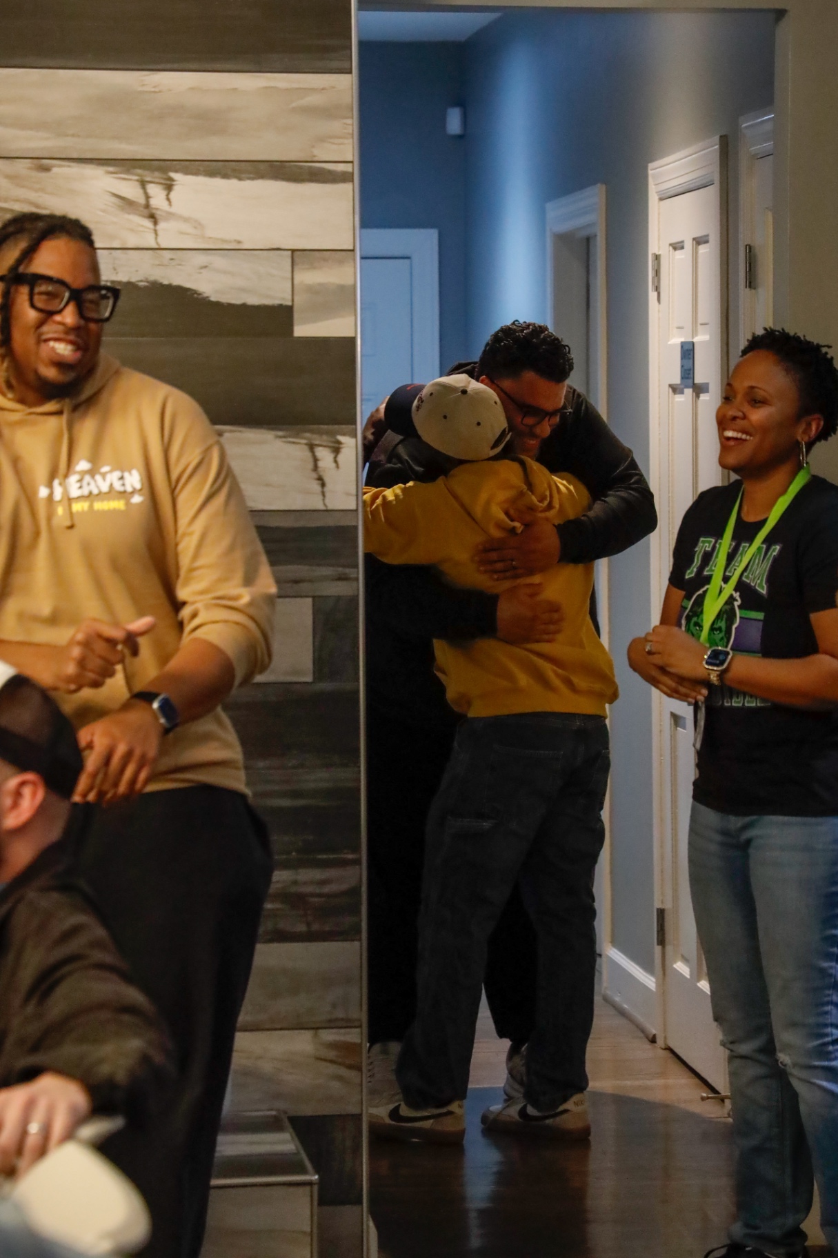 Attendees sharing a hug in the hallway while others smile nearby