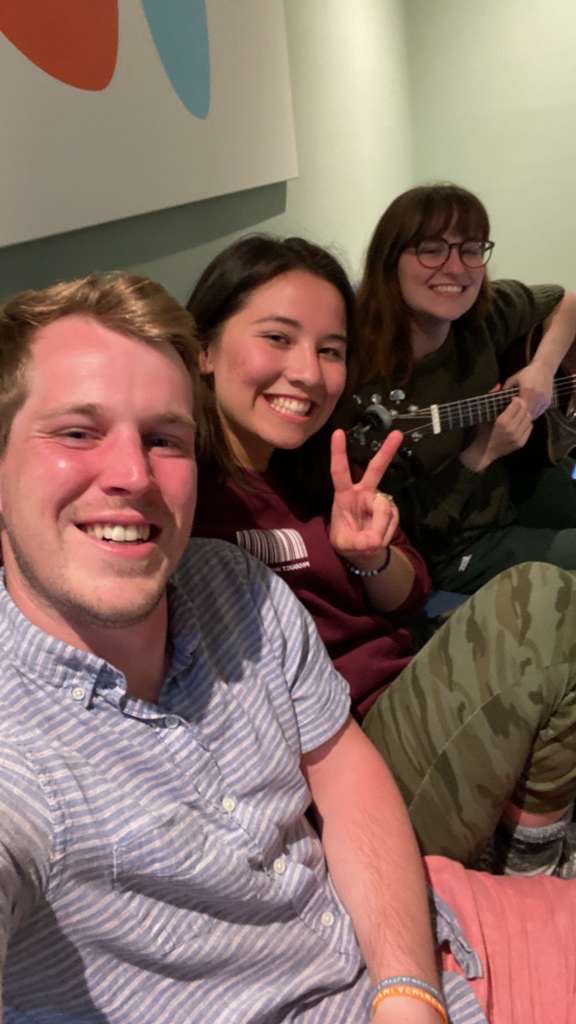 Three friends hanging out, one playing guitar