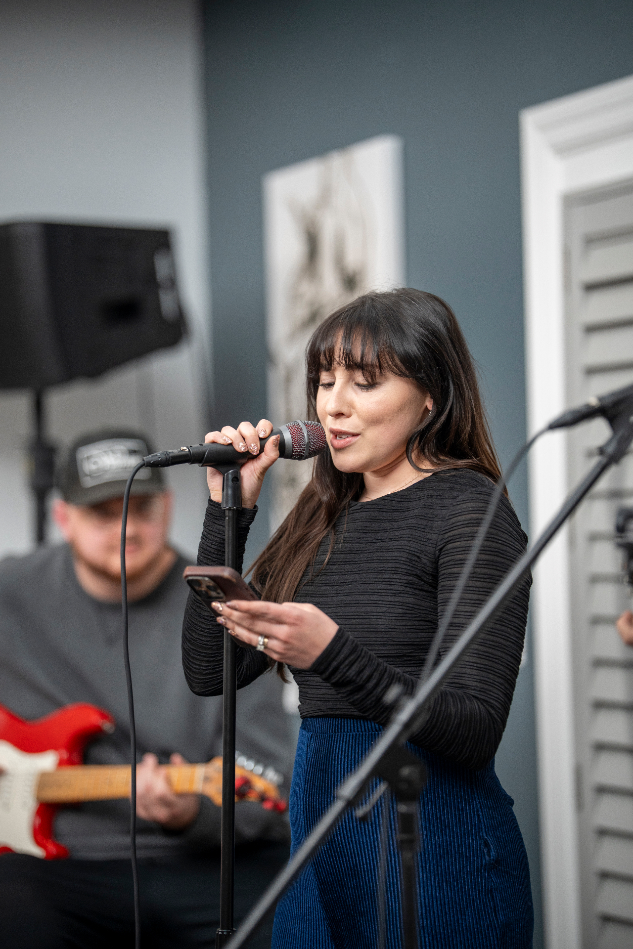 Performer singing into a microphone while holding lyrics on a phone