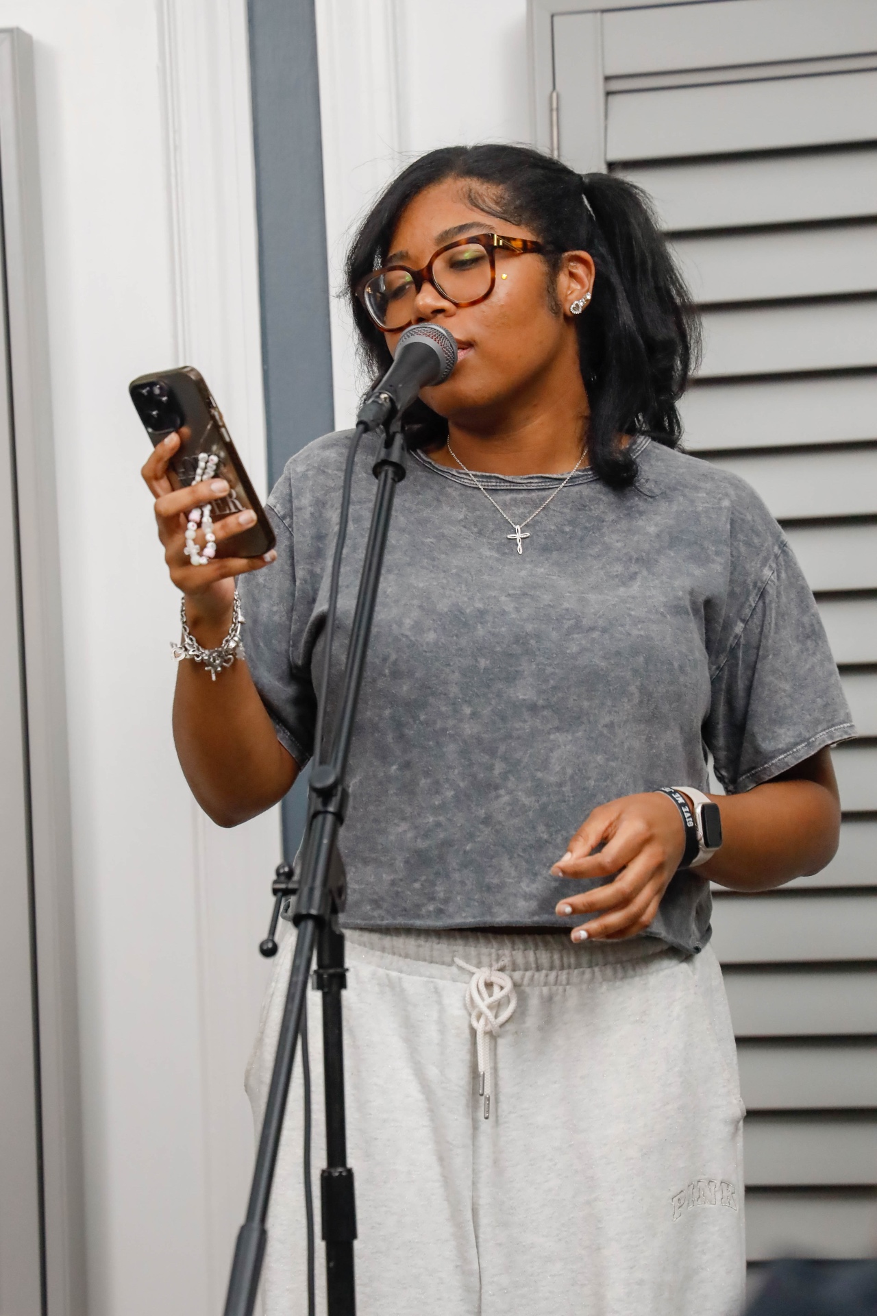 Young vocalist singing into a microphone while holding a phone
