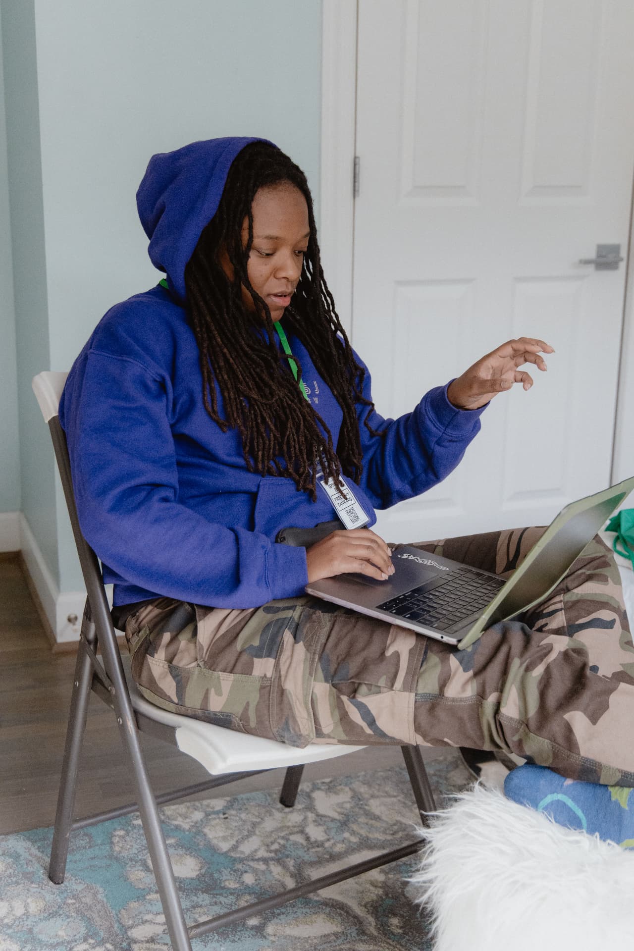 Writer in a blue hoodie working on a laptop from a chair