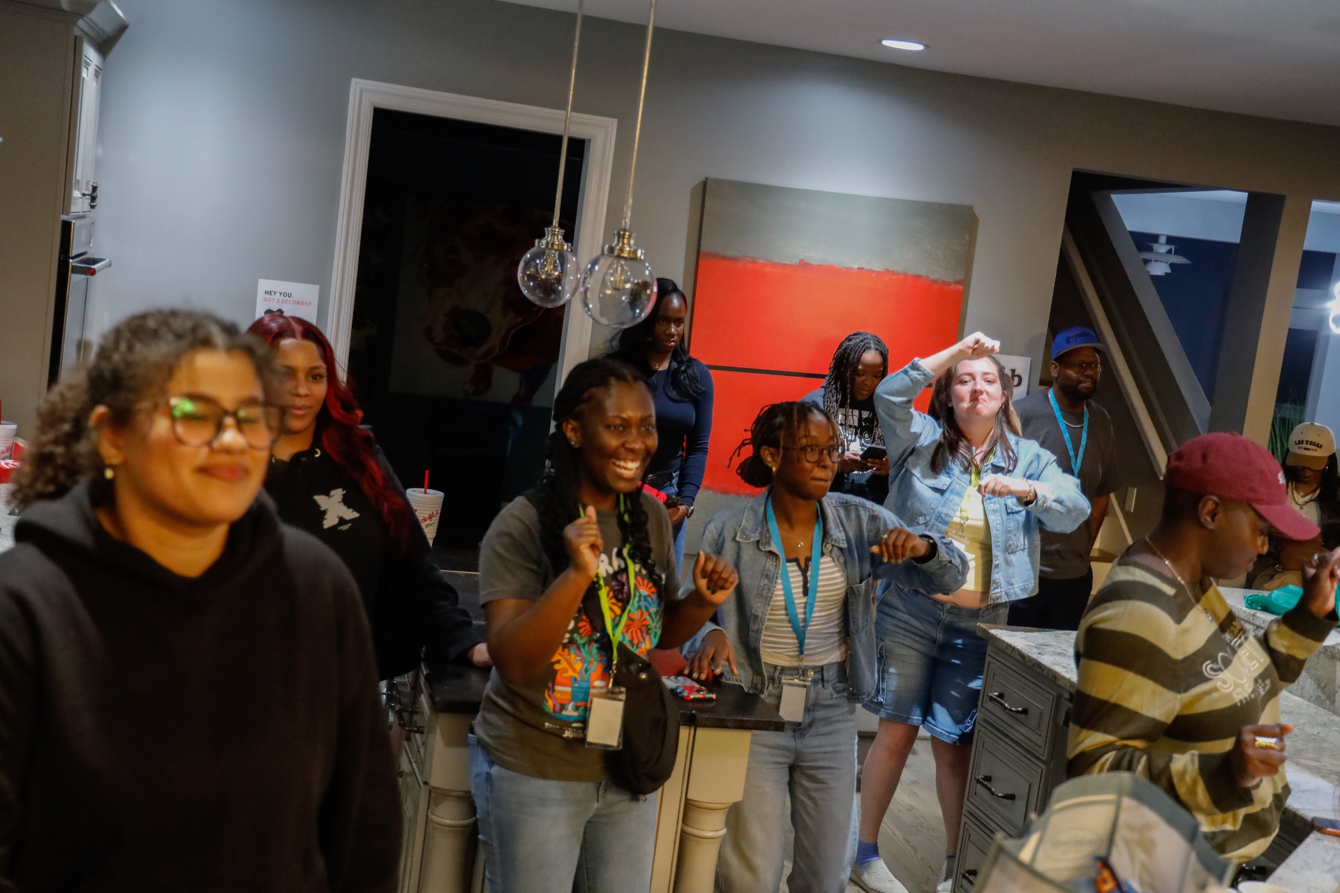 Attendees dancing and laughing together in the kitchen during an evening hang