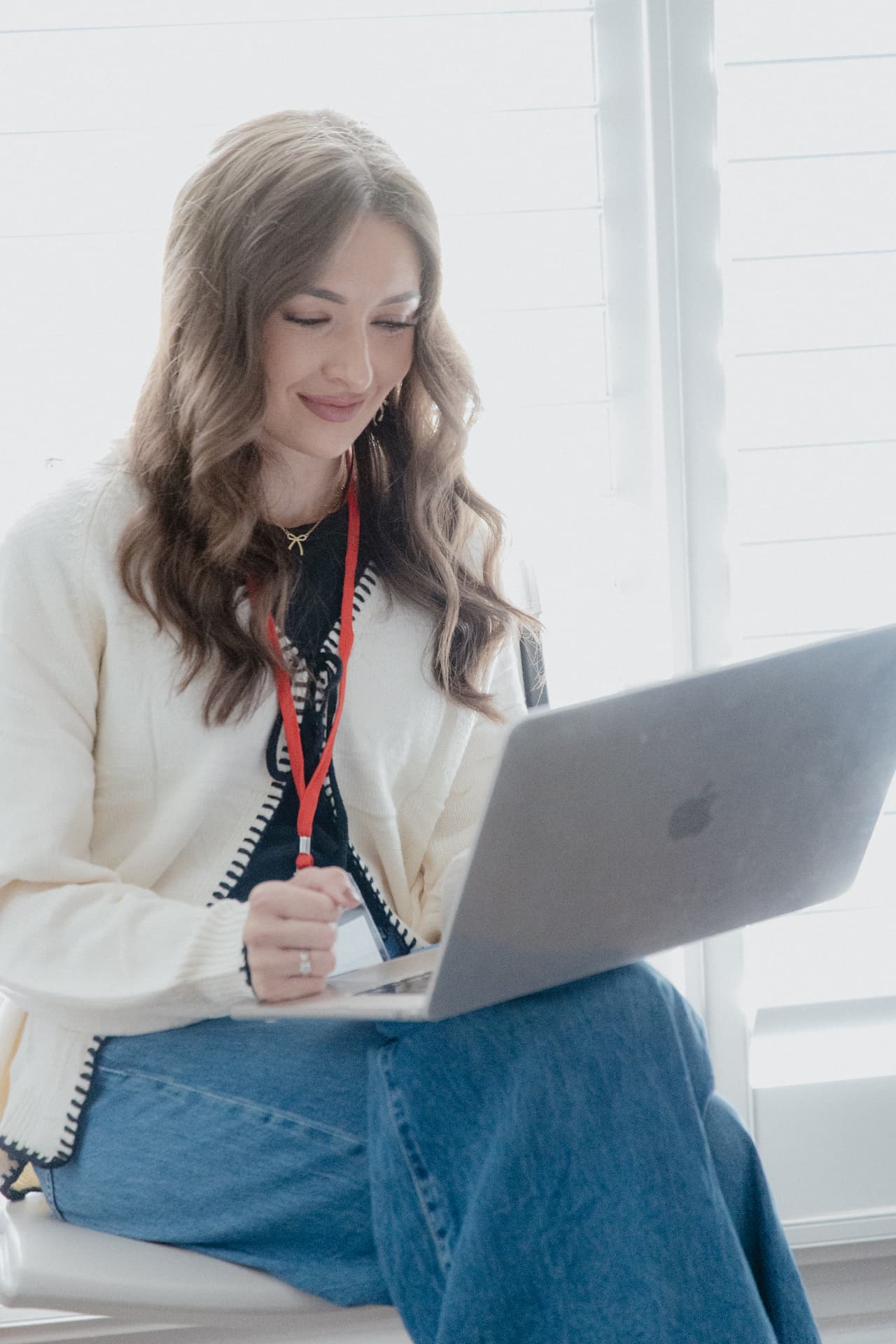 Songwriter smiling at her laptop with a lanyard around her neck