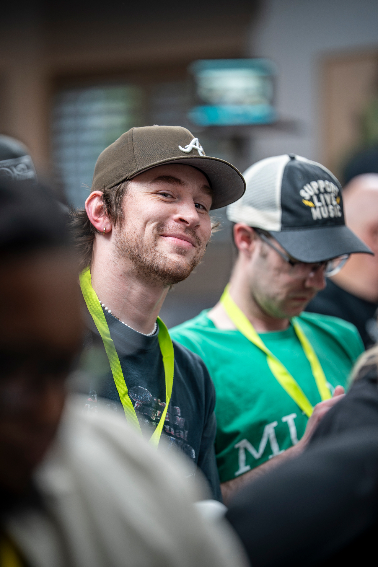 Attendee in a brown cap and neon lanyard smiling toward the camera