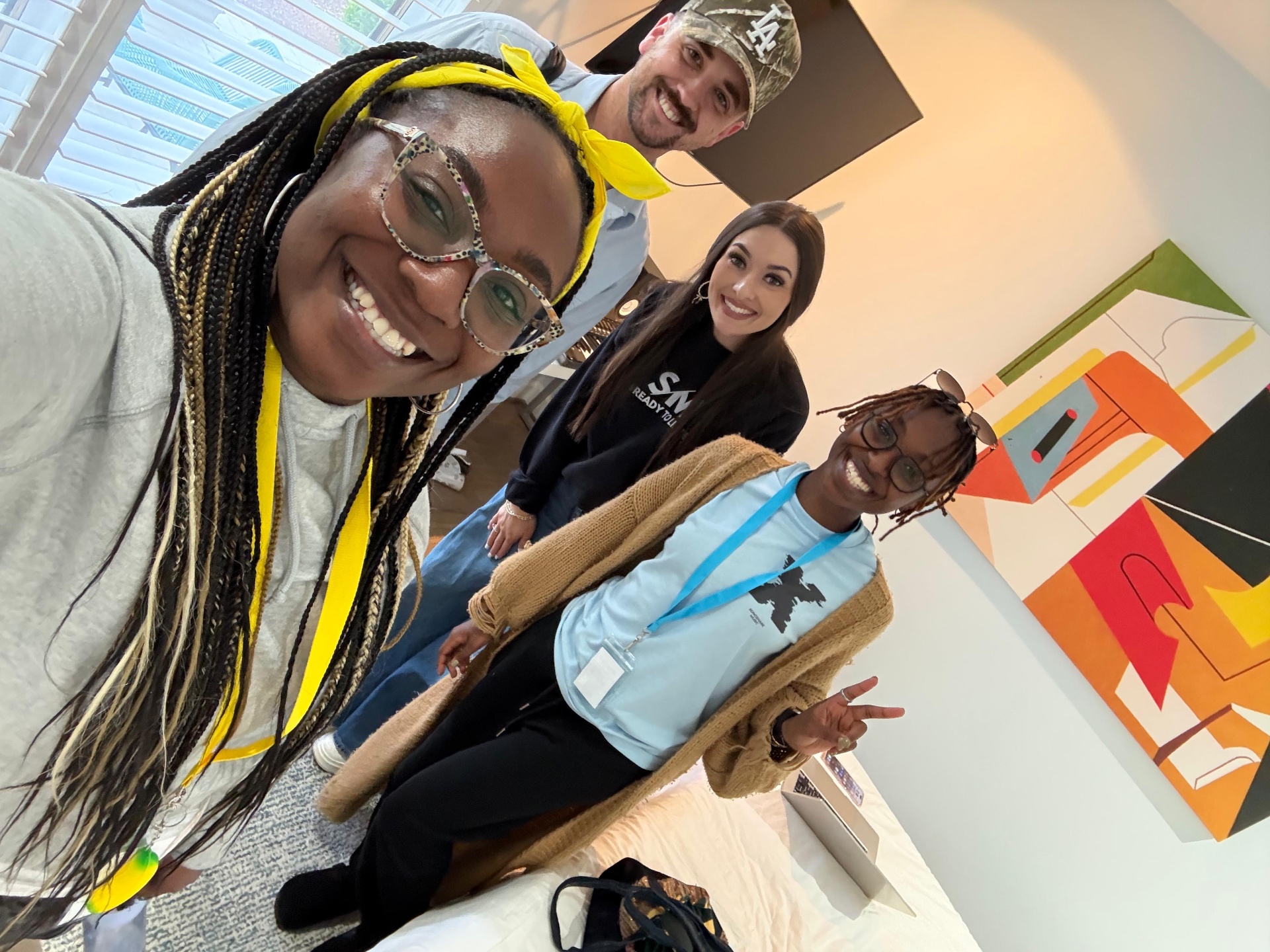 Selfie of four friends posing in front of artwork