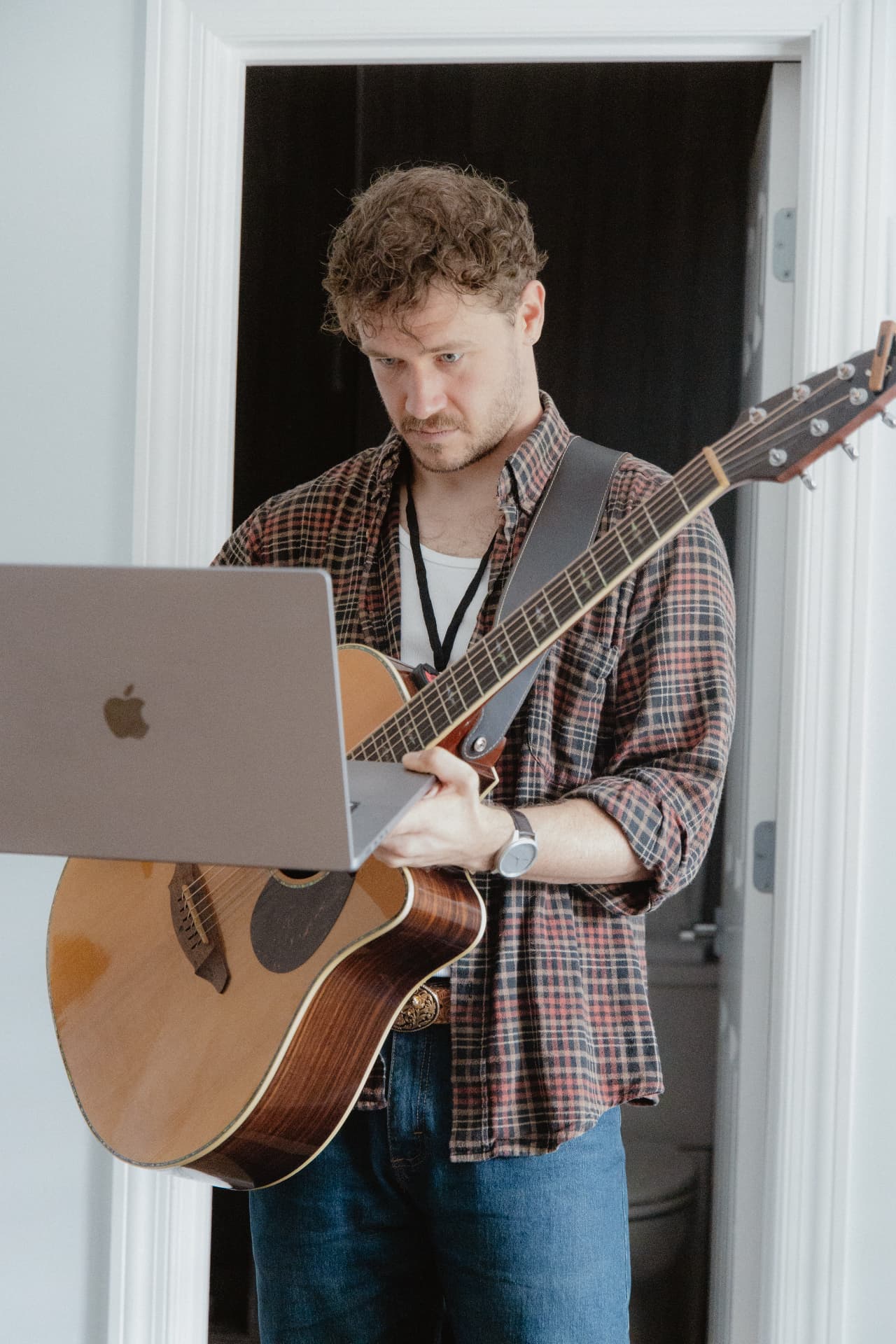 Songwriter playing guitar while reading lyrics from a laptop