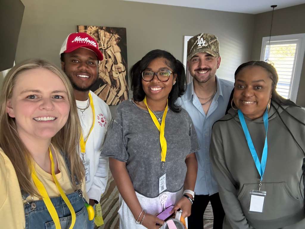 Five attendees smiling together with lanyards
