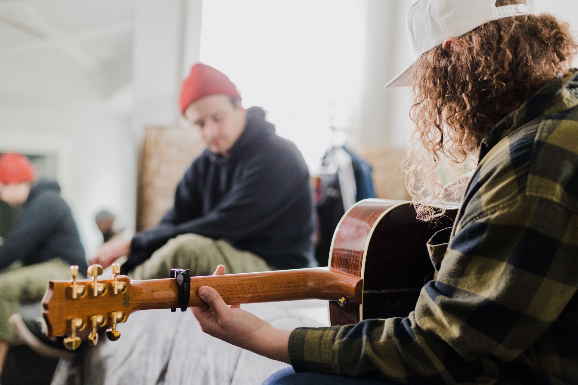 Guitarist with curly hair playing acoustic guitar during a writing session