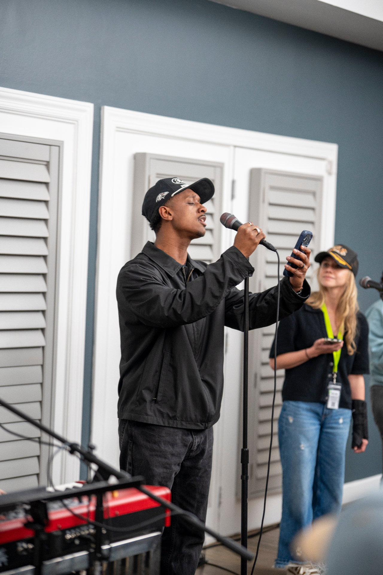 Solo vocalist performing into a microphone while reading lyrics from a phone