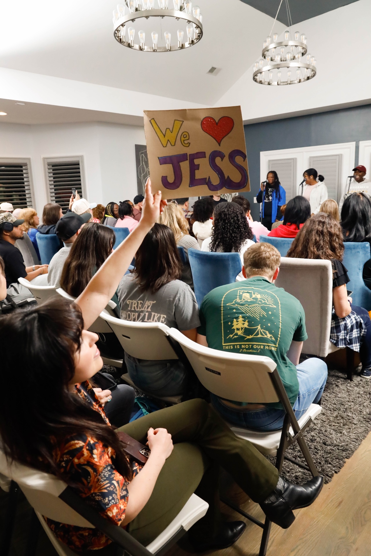 Attendee holding up a 'We love Jess' cardboard sign during an evening showcase