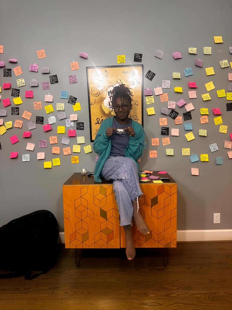 Attendee sitting in front of a wall covered in colorful handwritten notes