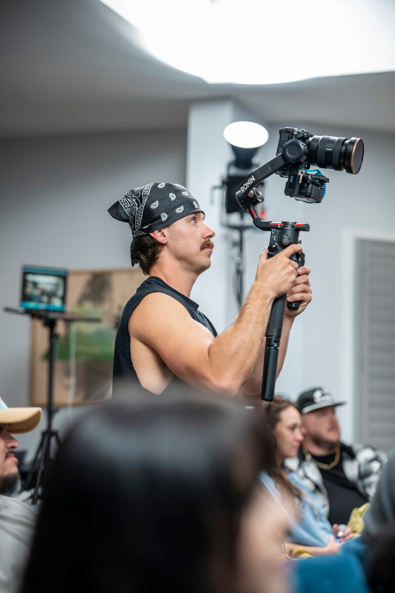 Videographer with a bandana filming the showcase on a gimbal rig