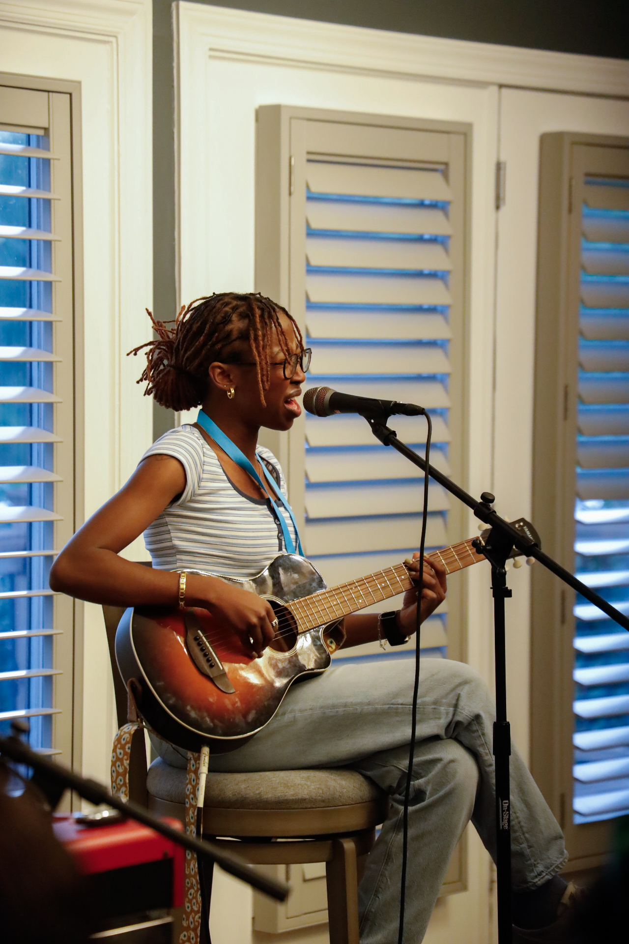 Young songwriter performing on guitar and singing into a microphone